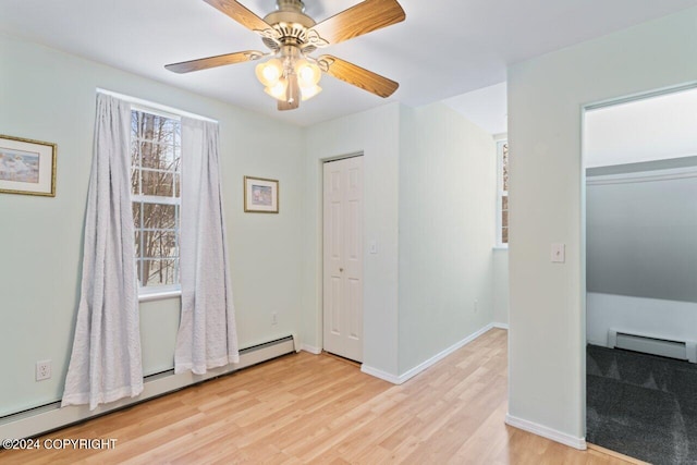 unfurnished bedroom featuring light hardwood / wood-style floors, a baseboard radiator, ceiling fan, and a closet