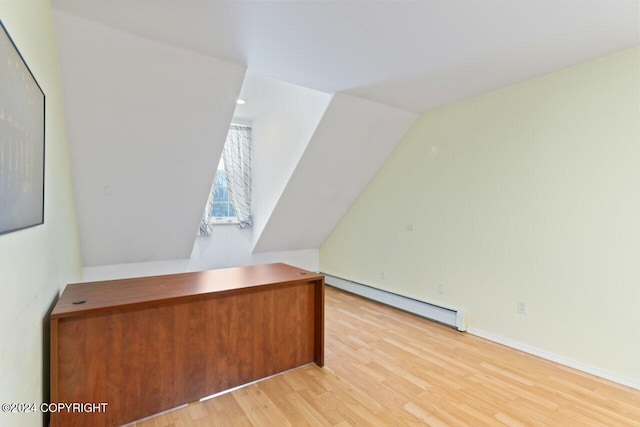 unfurnished office featuring a baseboard heating unit, light hardwood / wood-style flooring, and vaulted ceiling