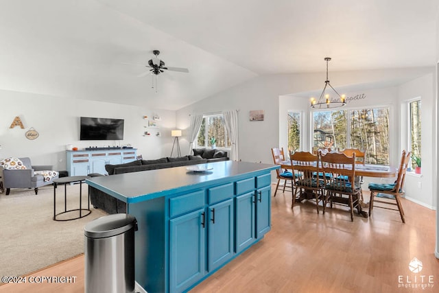 kitchen featuring a wealth of natural light, a kitchen island, vaulted ceiling, and blue cabinets