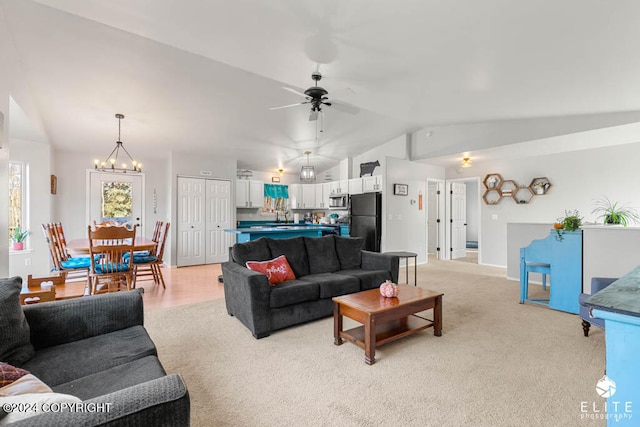 living room with ceiling fan with notable chandelier, lofted ceiling, light carpet, and sink