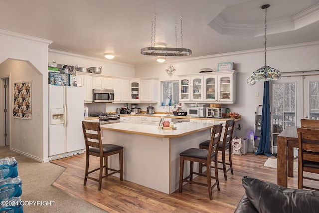 kitchen featuring ornamental molding, stainless steel appliances, light wood-type flooring, a kitchen bar, and a center island