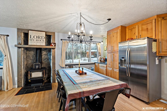 kitchen featuring a wood stove, light hardwood / wood-style floors, a textured ceiling, and stainless steel fridge with ice dispenser