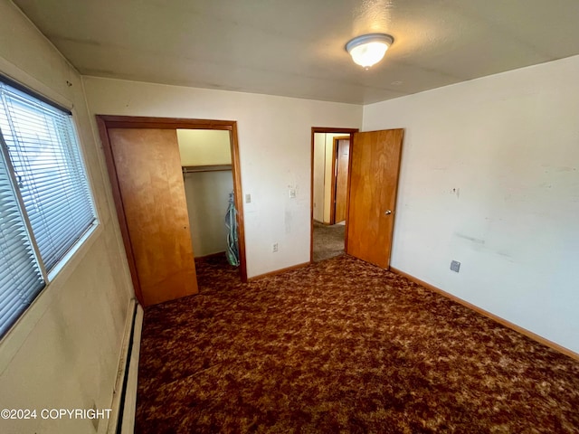 unfurnished bedroom with carpet floors, a closet, and a baseboard heating unit