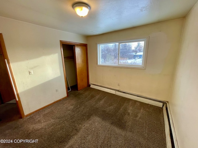 unfurnished bedroom with carpet floors, a closet, and a baseboard heating unit