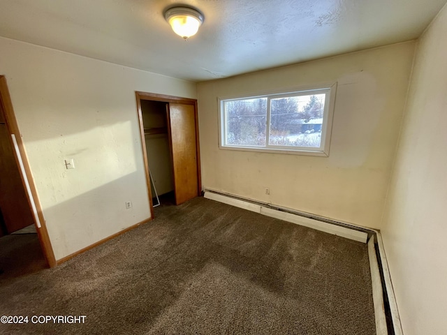 4312 E 6th Ave, Anchorage, AK 99508 - unfurnished bedroom with dark carpet, a closet, baseboard heating, a baseboard heating unit, and baseboards