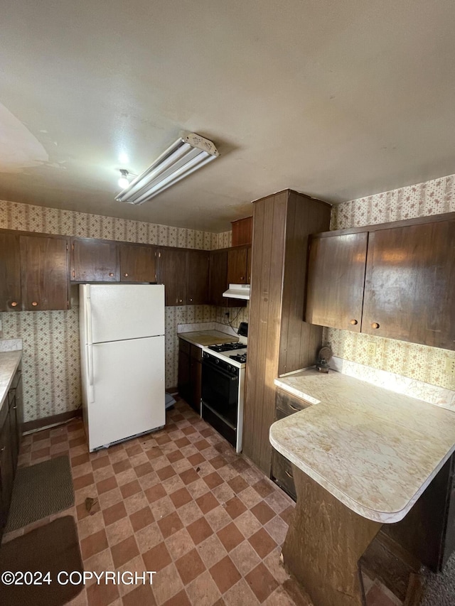 4312 E 6th Ave, Anchorage, AK 99508 - kitchen with freestanding refrigerator, range with gas cooktop, under cabinet range hood, light countertops, and wallpapered walls