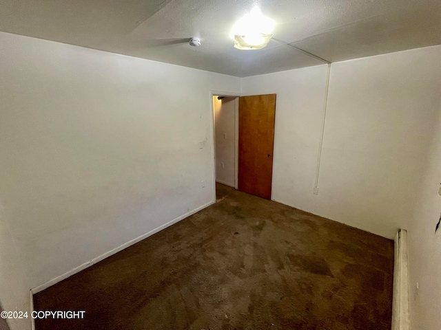 unfurnished room with dark colored carpet and baseboard heating