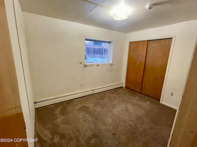 unfurnished bedroom with a closet, carpet, and a baseboard heating unit