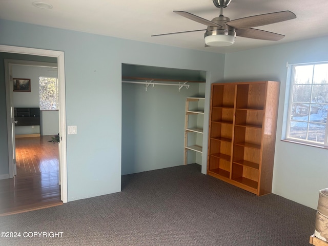 unfurnished bedroom featuring a closet, multiple windows, hardwood / wood-style flooring, and ceiling fan