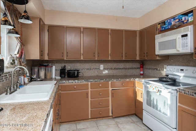 kitchen with a textured ceiling, light tile patterned floors, white appliances, a sink, and tasteful backsplash