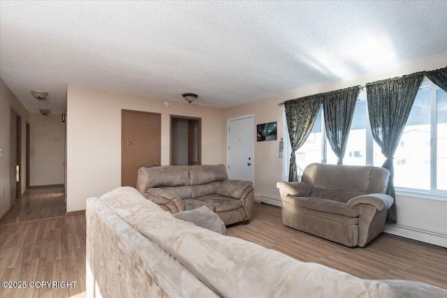 living area with a textured ceiling, baseboard heating, and wood finished floors