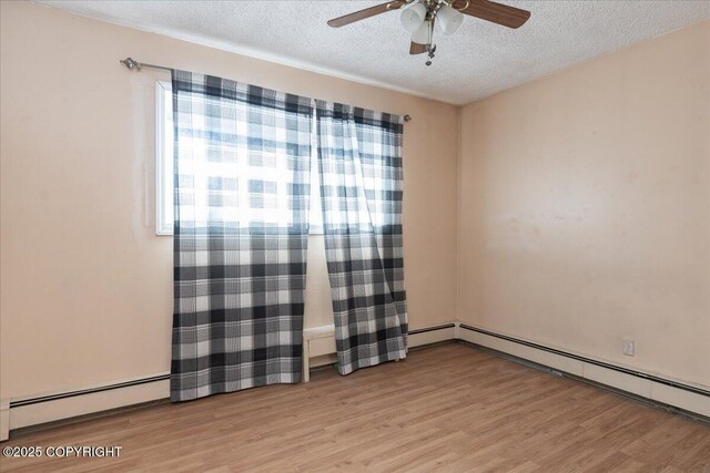 empty room featuring a baseboard heating unit, ceiling fan, light wood-style flooring, and a textured ceiling