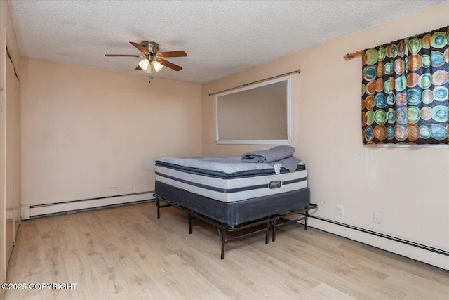 bedroom featuring a baseboard heating unit, a textured ceiling, and wood finished floors