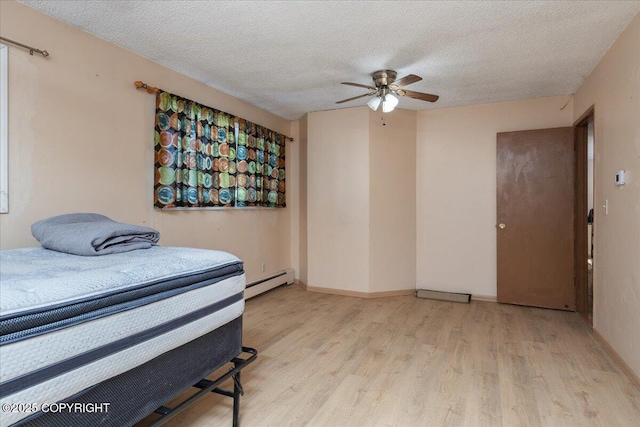 bedroom featuring baseboards, a ceiling fan, wood finished floors, baseboard heating, and a textured ceiling