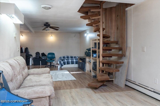 living area with a baseboard heating unit, wood finished floors, and a ceiling fan