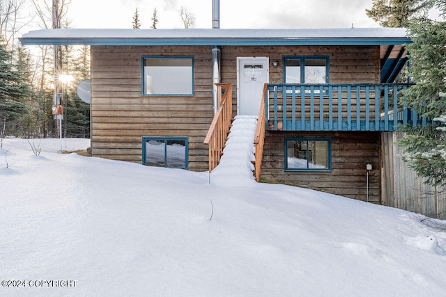 snow covered rear of property with a balcony