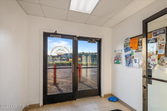 doorway featuring a drop ceiling and light tile patterned floors