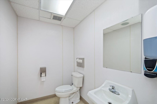 bathroom with toilet, a paneled ceiling, and sink