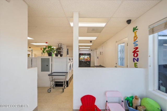 interior space featuring carpet flooring, electric panel, a paneled ceiling, and washer / dryer