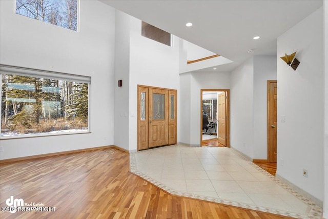 foyer entrance with a towering ceiling and light hardwood / wood-style flooring