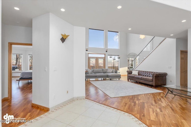 living room featuring a high ceiling, light hardwood / wood-style flooring, and plenty of natural light