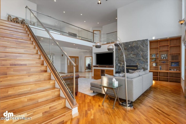 living room featuring a fireplace, light hardwood / wood-style flooring, and a towering ceiling