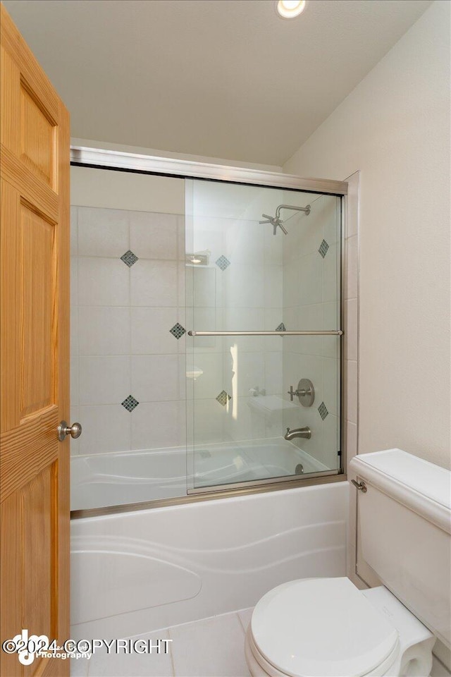 bathroom with combined bath / shower with glass door, tile patterned floors, and toilet