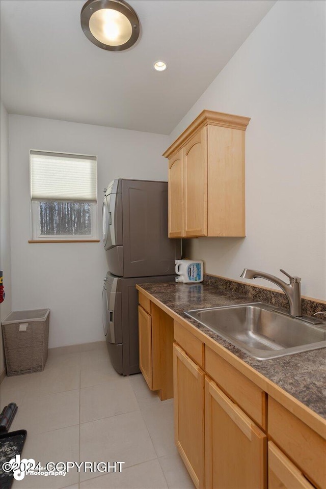 kitchen with light tile patterned flooring, light brown cabinetry, stacked washer and dryer, and sink