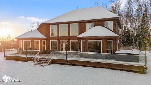 snow covered house featuring a wooden deck