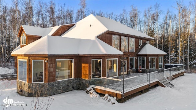 snow covered rear of property featuring a deck