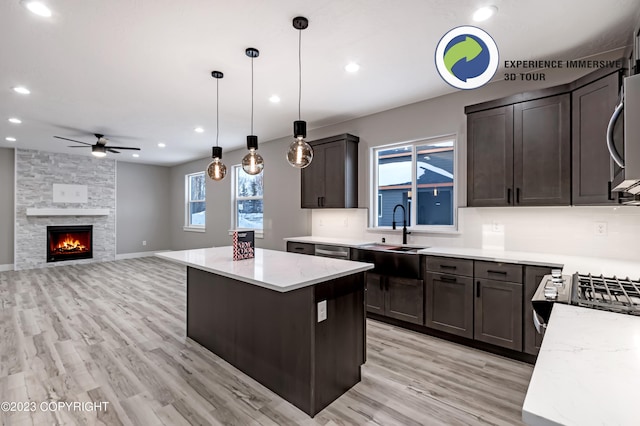 kitchen featuring ceiling fan, a kitchen island, sink, and decorative light fixtures