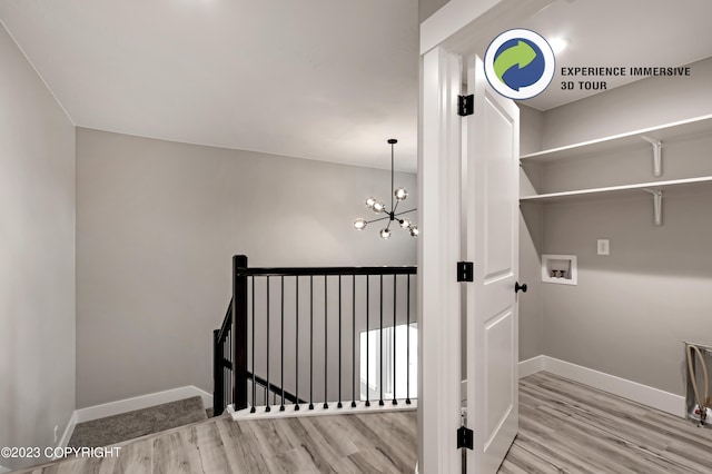 laundry room featuring light hardwood / wood-style flooring, hookup for a washing machine, and an inviting chandelier