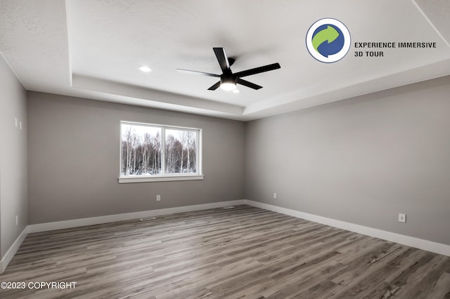 spare room featuring ceiling fan, a raised ceiling, and wood-type flooring