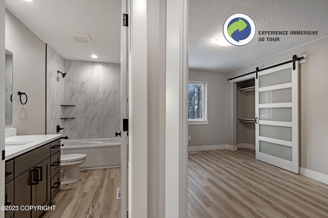 full bathroom featuring vanity, a textured ceiling, wood-type flooring, toilet, and tiled shower / bath