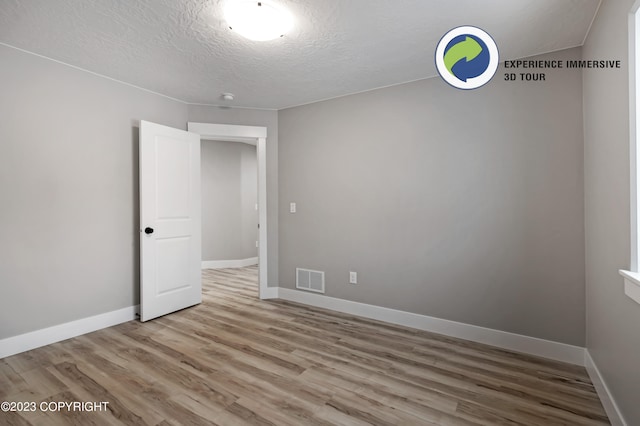 empty room featuring a textured ceiling and light wood-type flooring