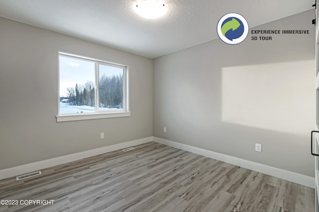 unfurnished room featuring a textured ceiling and light wood-type flooring