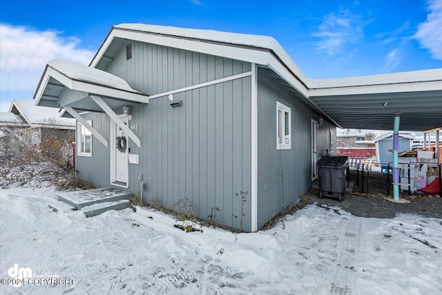 view of snowy exterior with a carport