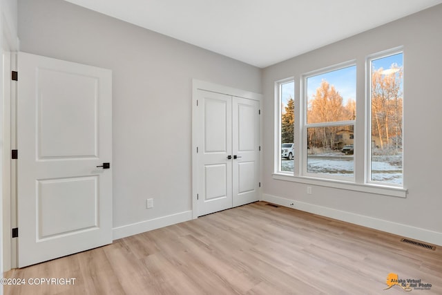 unfurnished bedroom with light wood-type flooring and a closet