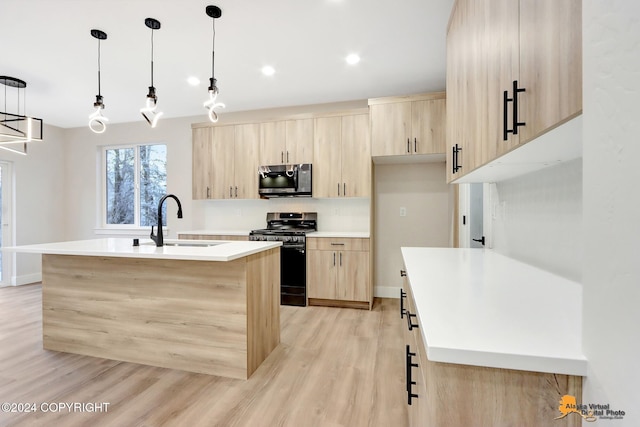 kitchen featuring stainless steel appliances, sink, light brown cabinets, and an island with sink