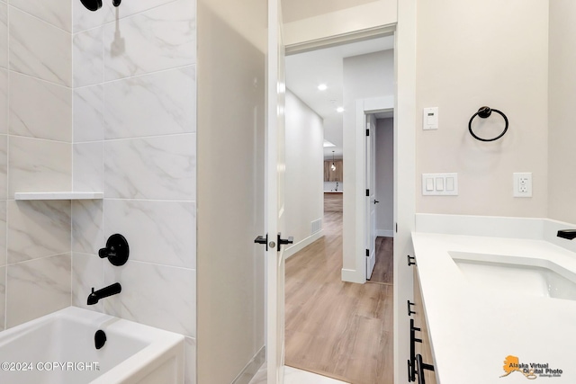 bathroom with tiled shower / bath combo, hardwood / wood-style flooring, and vanity