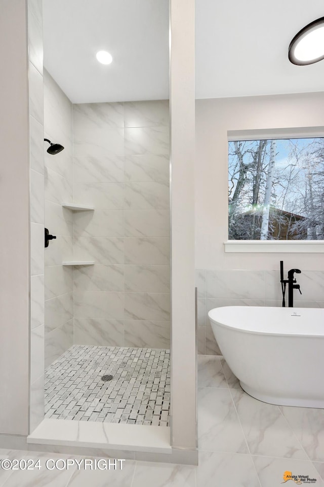 bathroom featuring tile walls and separate shower and tub