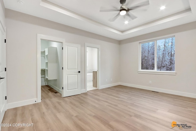 unfurnished bedroom with a raised ceiling, a walk in closet, a closet, and connected bathroom