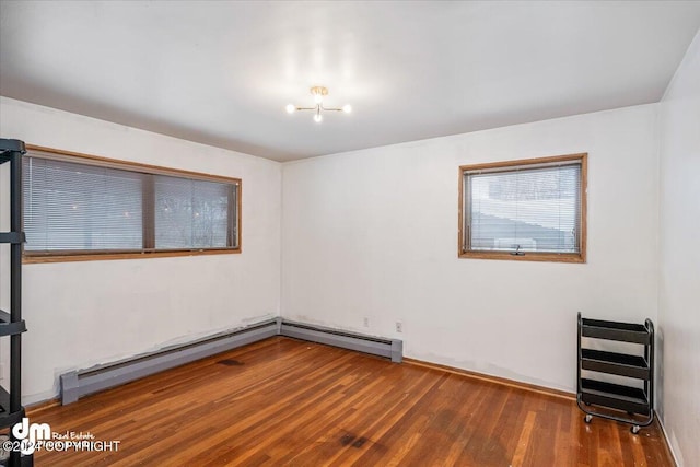 unfurnished room featuring hardwood / wood-style floors and a baseboard heating unit