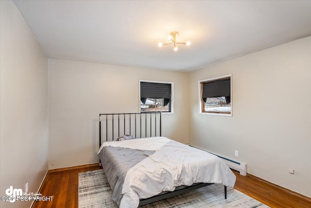 bedroom featuring hardwood / wood-style floors, a chandelier, and a baseboard heating unit