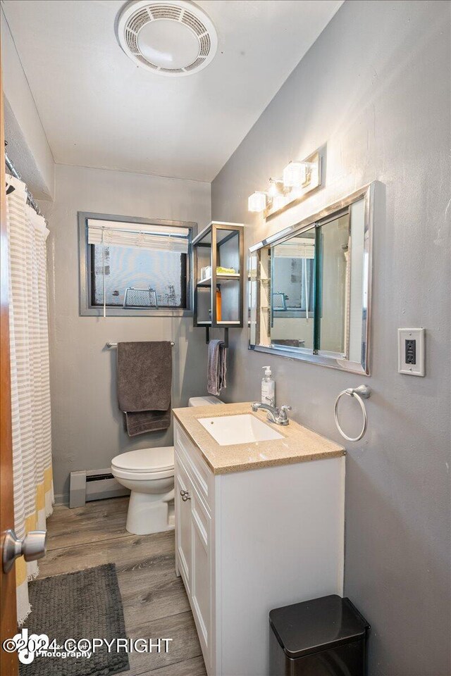 bathroom featuring wood-type flooring, toilet, a baseboard heating unit, and vanity