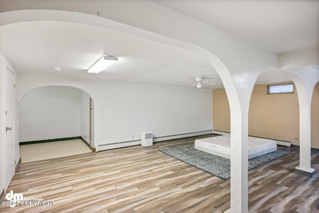 exercise room featuring hardwood / wood-style flooring, a baseboard radiator, and ceiling fan