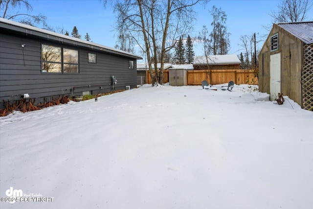 snowy yard featuring a storage shed