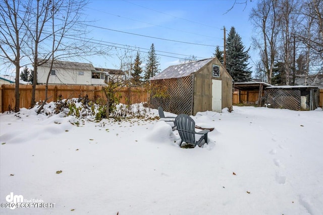 snowy yard featuring a storage shed