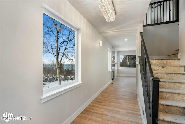 hall featuring an inviting chandelier and light wood-type flooring