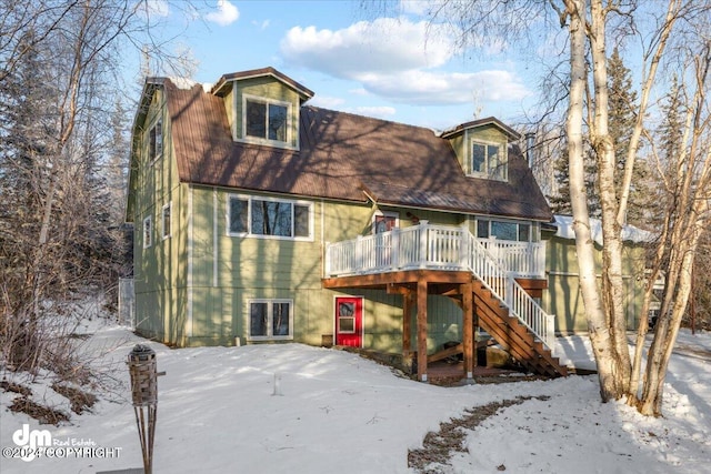 snow covered house with a wooden deck